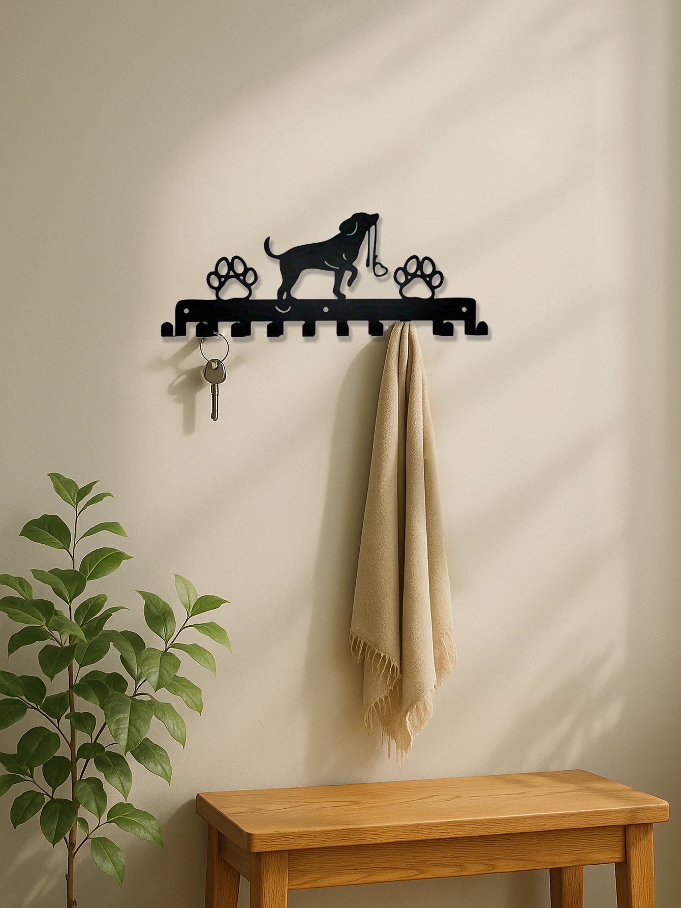 Wall-mounted coat rack with dog design, key holder, and towel on a beige wall.