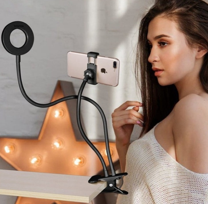 Woman using a smartphone with a flexible stand in front of a decorative lamp.