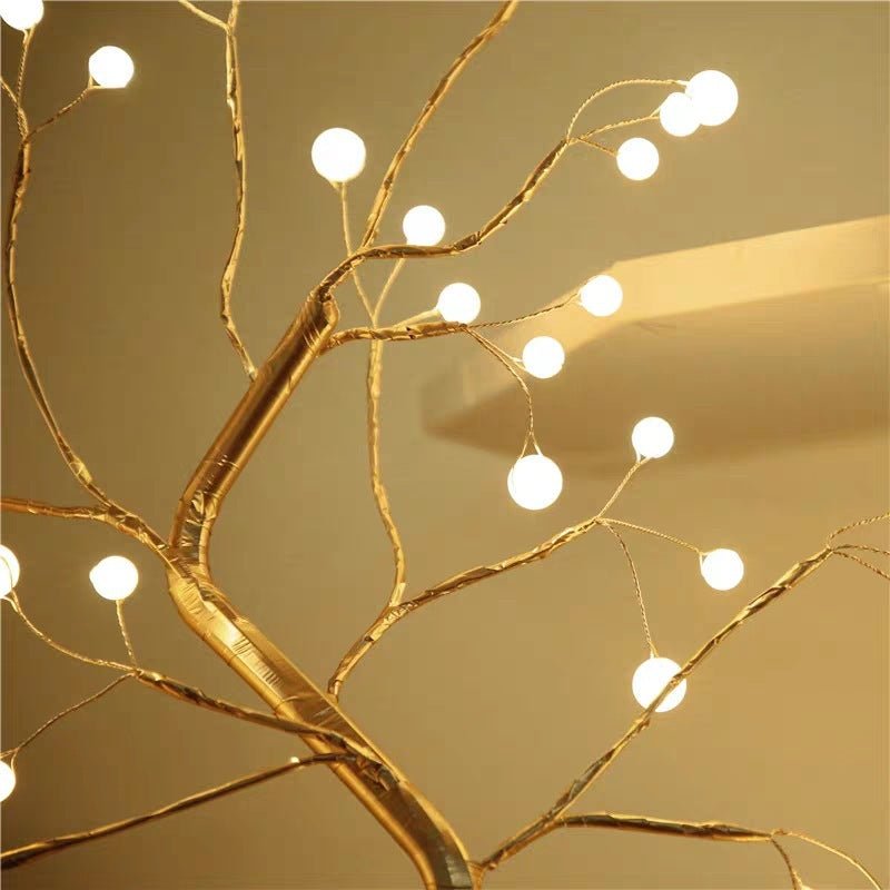 Decorative gold branch with string lights against a beige background