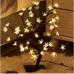 Decorative LED tree with illuminated branches on a soft surface.