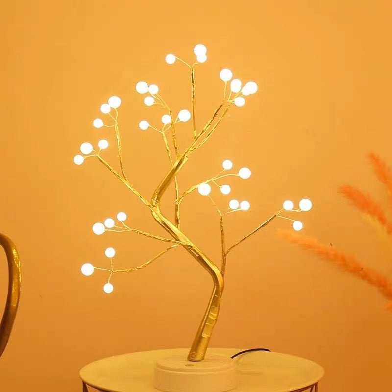 Decorative LED tree with white lights on a gold branch against an orange background