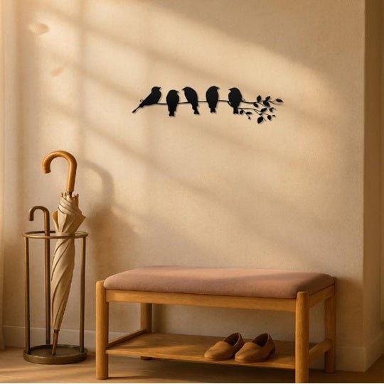 Decorative wall art of birds on a branch above a wooden bench with shoes underneath.
