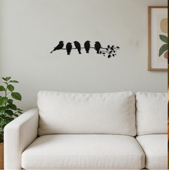 Decorative wall art of birds on a branch above a white sofa.