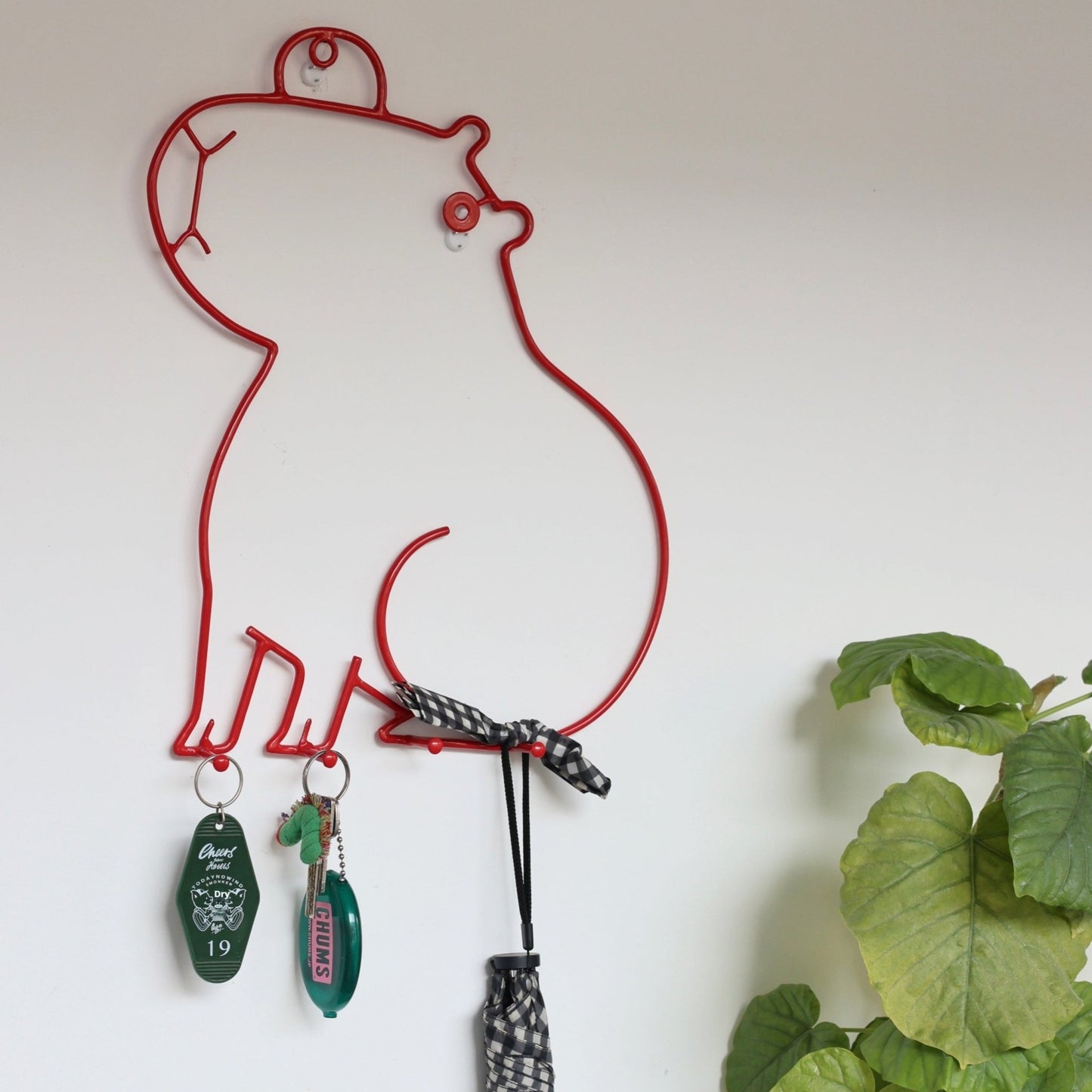 Red wire wall hook with decorative items on a white wall