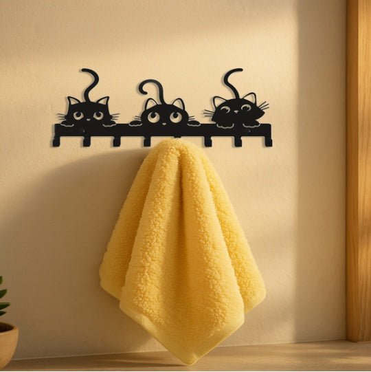 Black cat-shaped wall hook with a yellow towel on a light-colored wall.