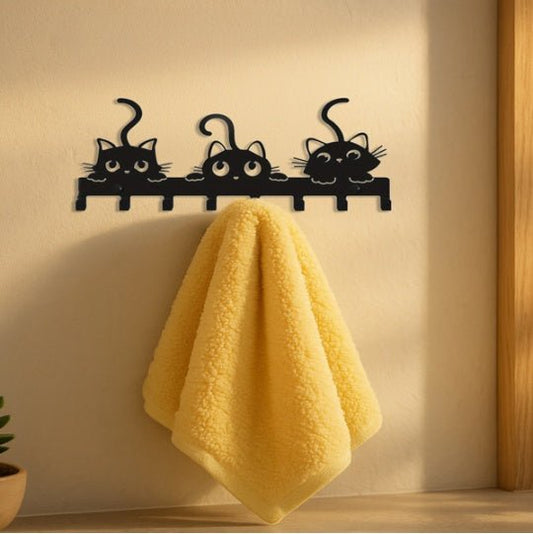 Black cat-shaped wall hook with a yellow towel on a light-colored wall.