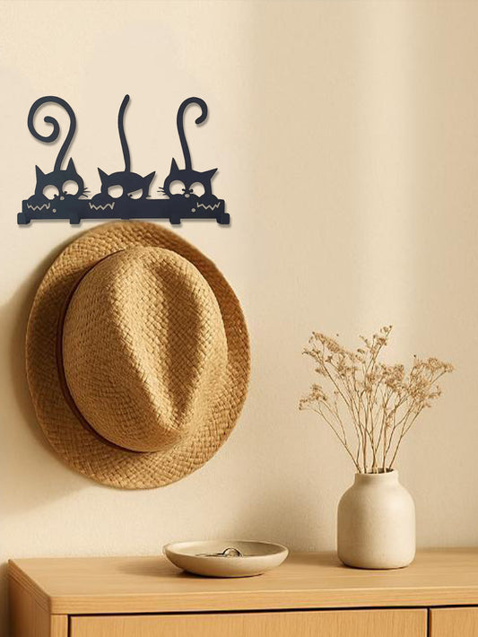 Wall-mounted metal coat rack with a straw hat and decorative vase on a wooden surface.