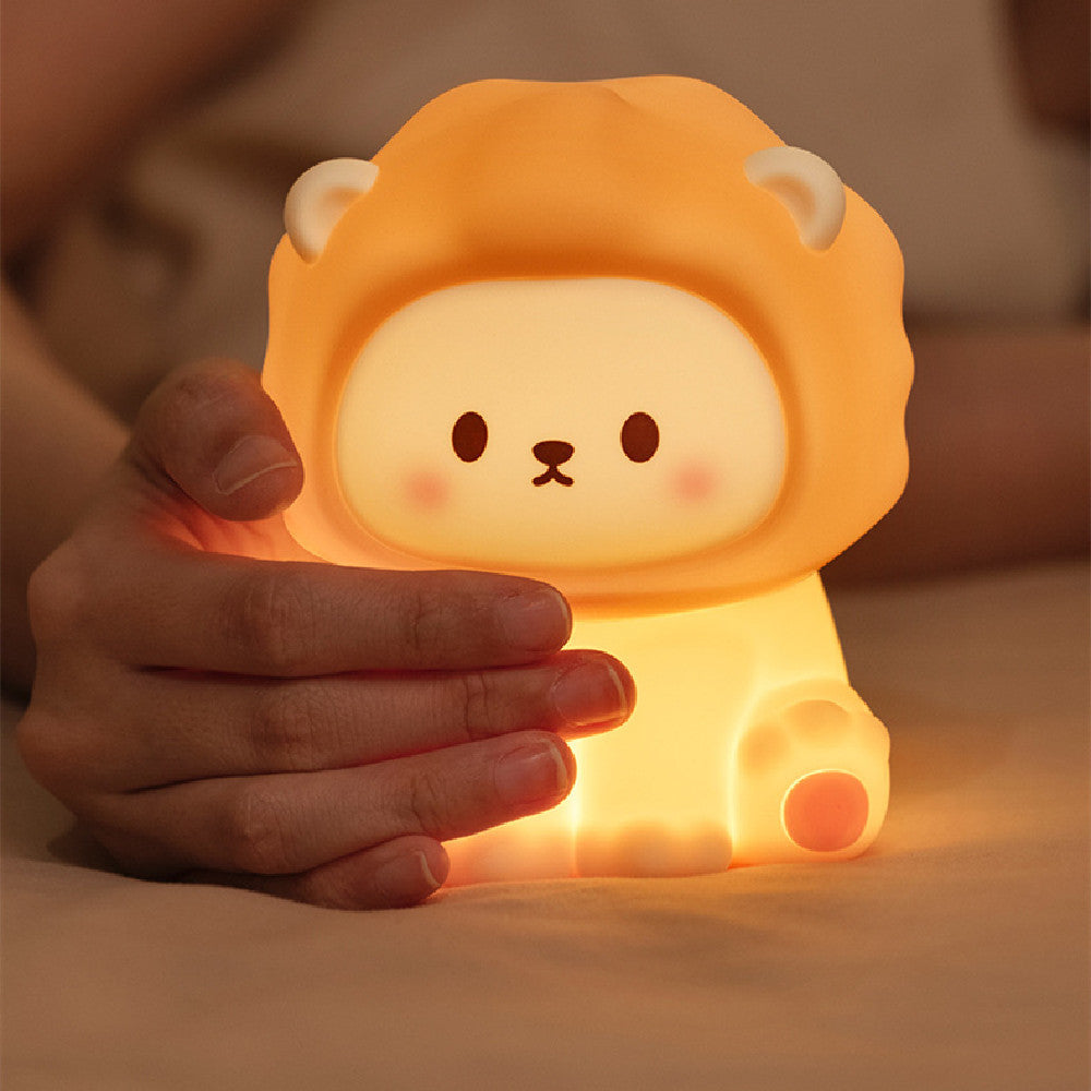 Cute lion-shaped night light held by a hand with a warm glow.