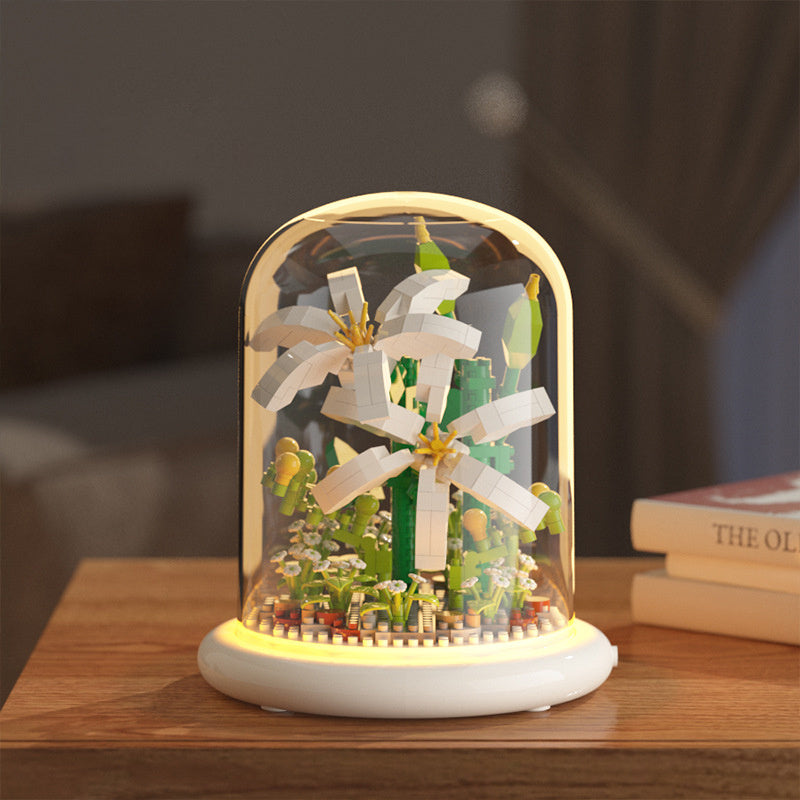 Decorative lamp with windmill and plants inside a glass dome on a wooden surface.