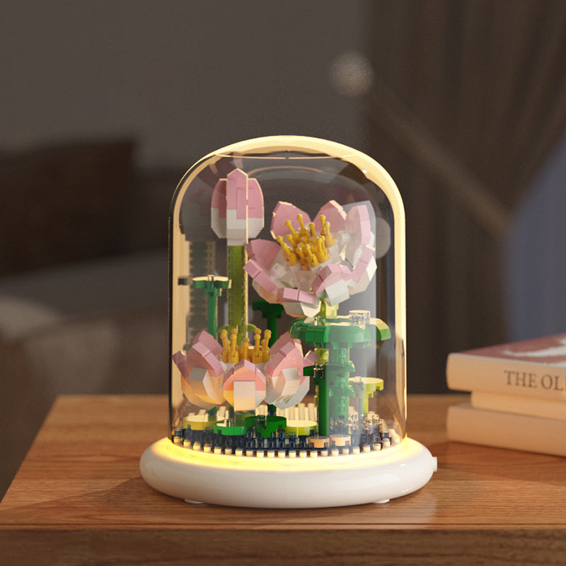 Decorative lamp with floral design inside a glass dome on a wooden surface.