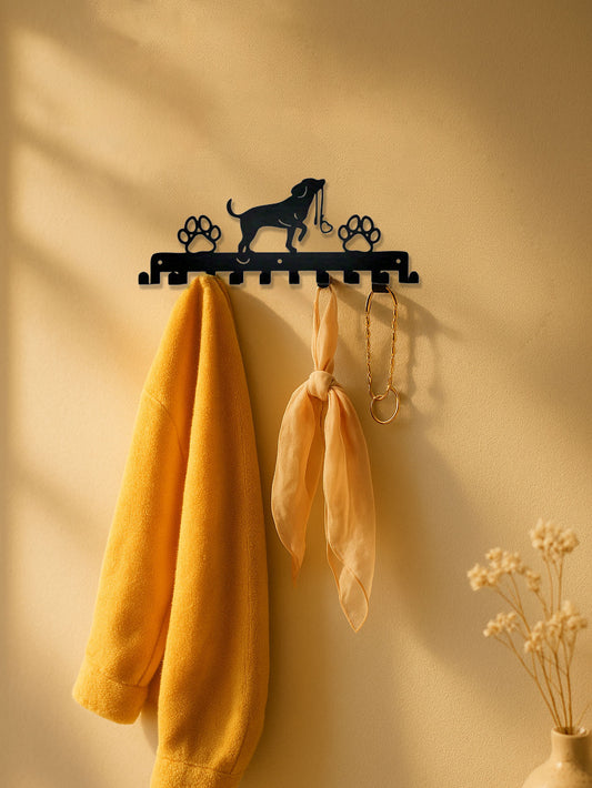 Decorative wall hook with a dog design on a beige wall with a yellow garment and scarf hanging from it.