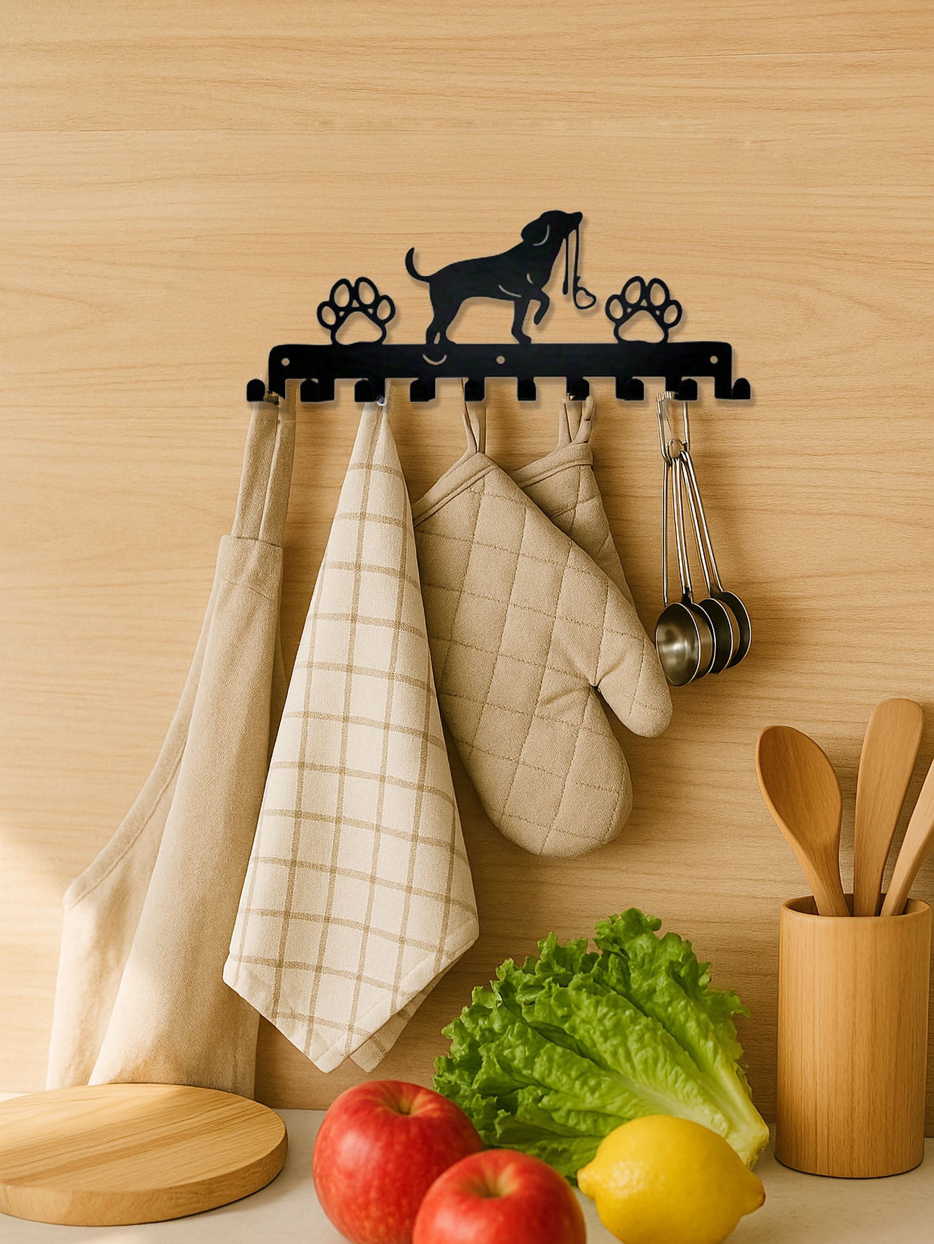 Decorative wall hook with dog design hanging kitchen items on a wooden wall.