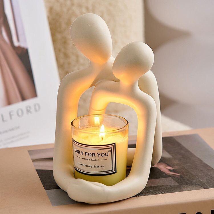 Ceramic sculpture of two figures holding a candle labeled 'Only For You' on a table.