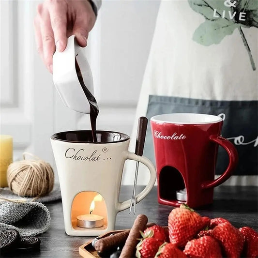 Person pouring chocolate into a white mug with a red 'Chocolate' mug in the background, surrounded by strawberries and cinnamon sticks.