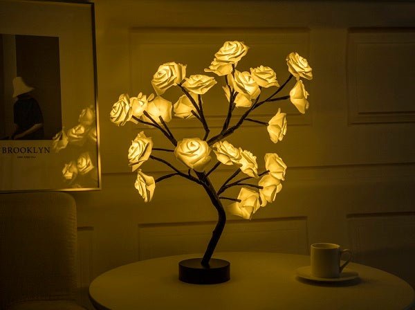 Decorative LED lamp shaped like a tree with illuminated flowers on a table.
