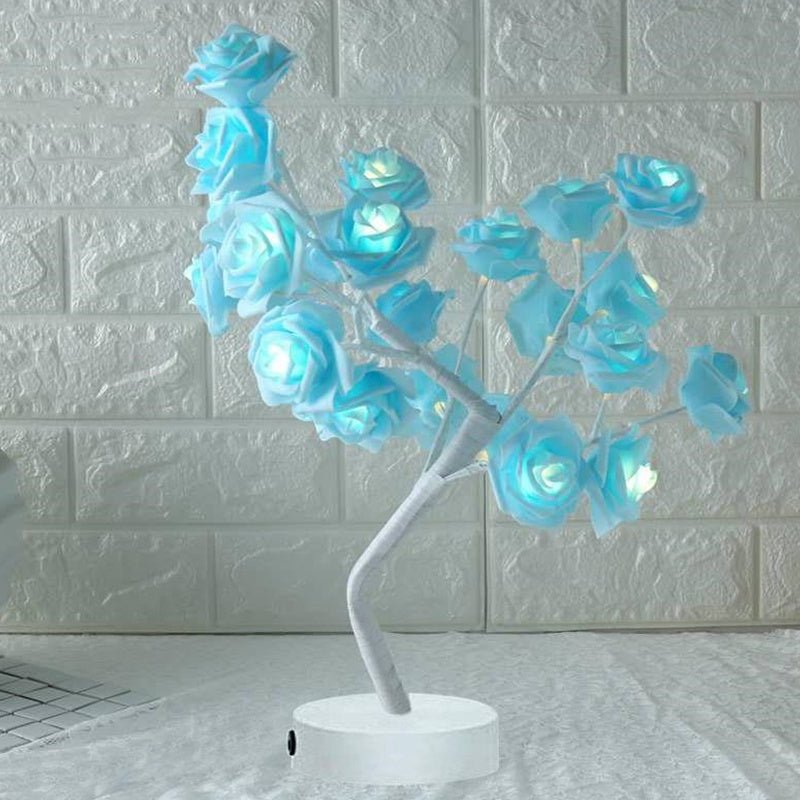 Decorative lamp with blue LED roses on a white base against a textured wall.