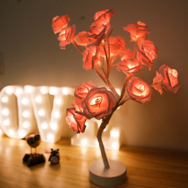 Decorative LED flower lamp on a wooden surface with 'LOVE' sign in the background