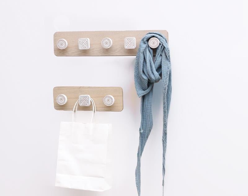 Wooden wall hook with multiple hooks holding a blue scarf and white bag on a white background
