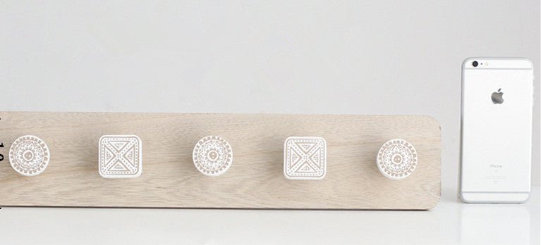 Wooden pegboard with decorative stickers and a smartphone on a light gray background